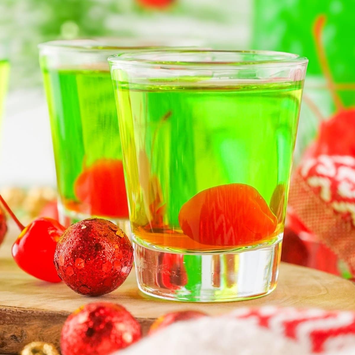 Two glasses of Grinch Shots with cherries.