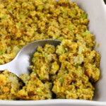 A dish of cornbread stuffing with a serving spoon.