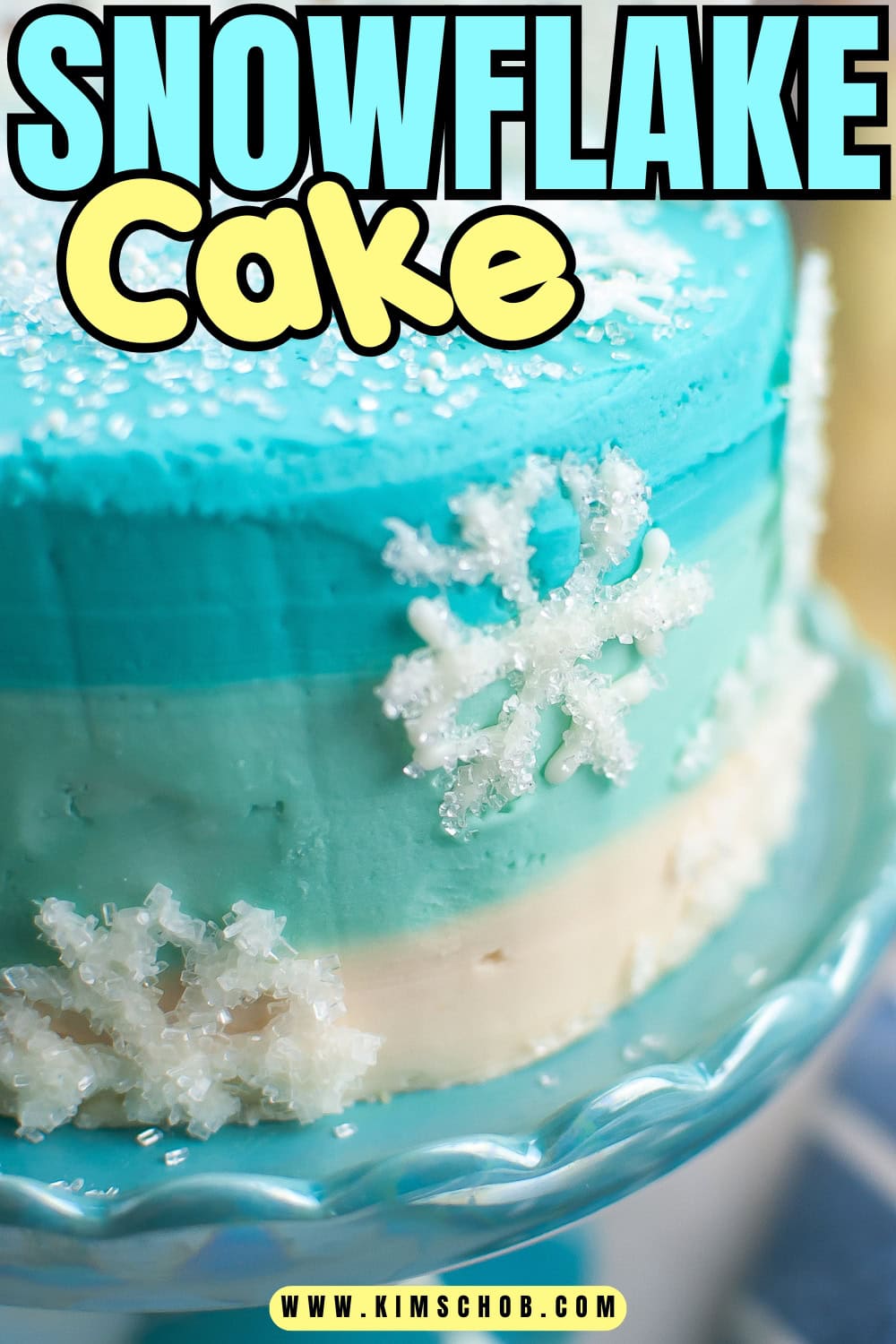Blue and white snowflake-themed cake on a decorative glass stand.