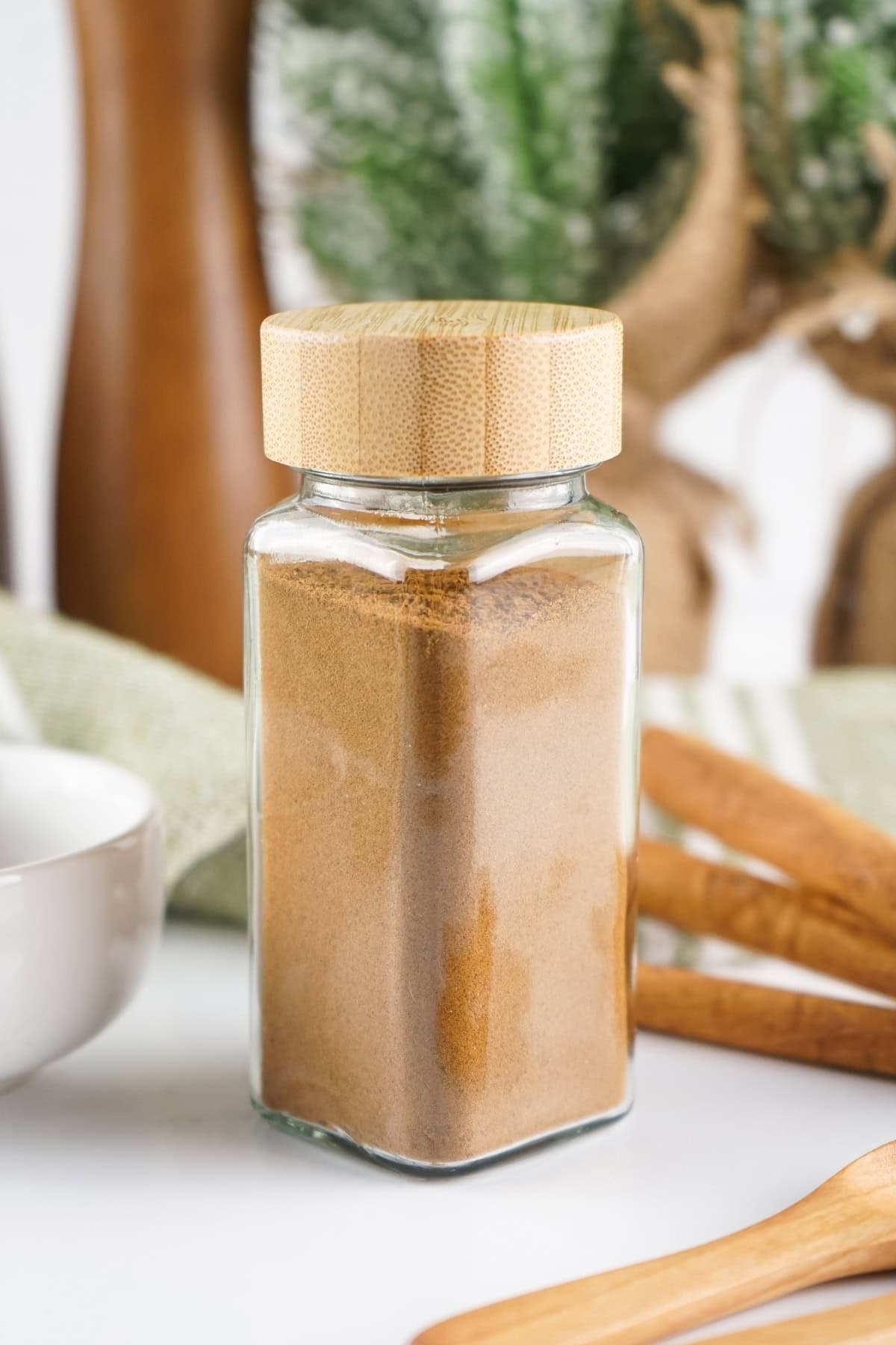 Glass jar filled spice blend, with wooden lid, on a kitchen counter.