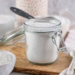 A jar of Powdered Sugar on a wooden board.
