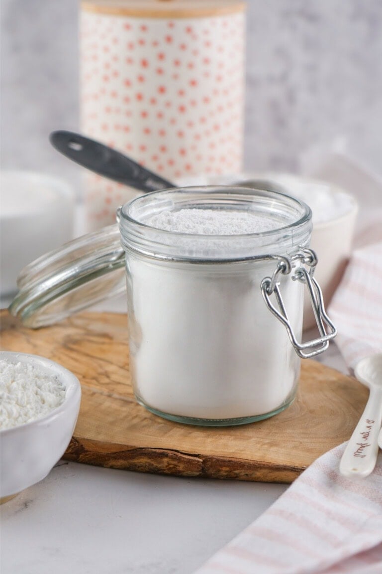 A jar of Powdered Sugar on a wooden board.