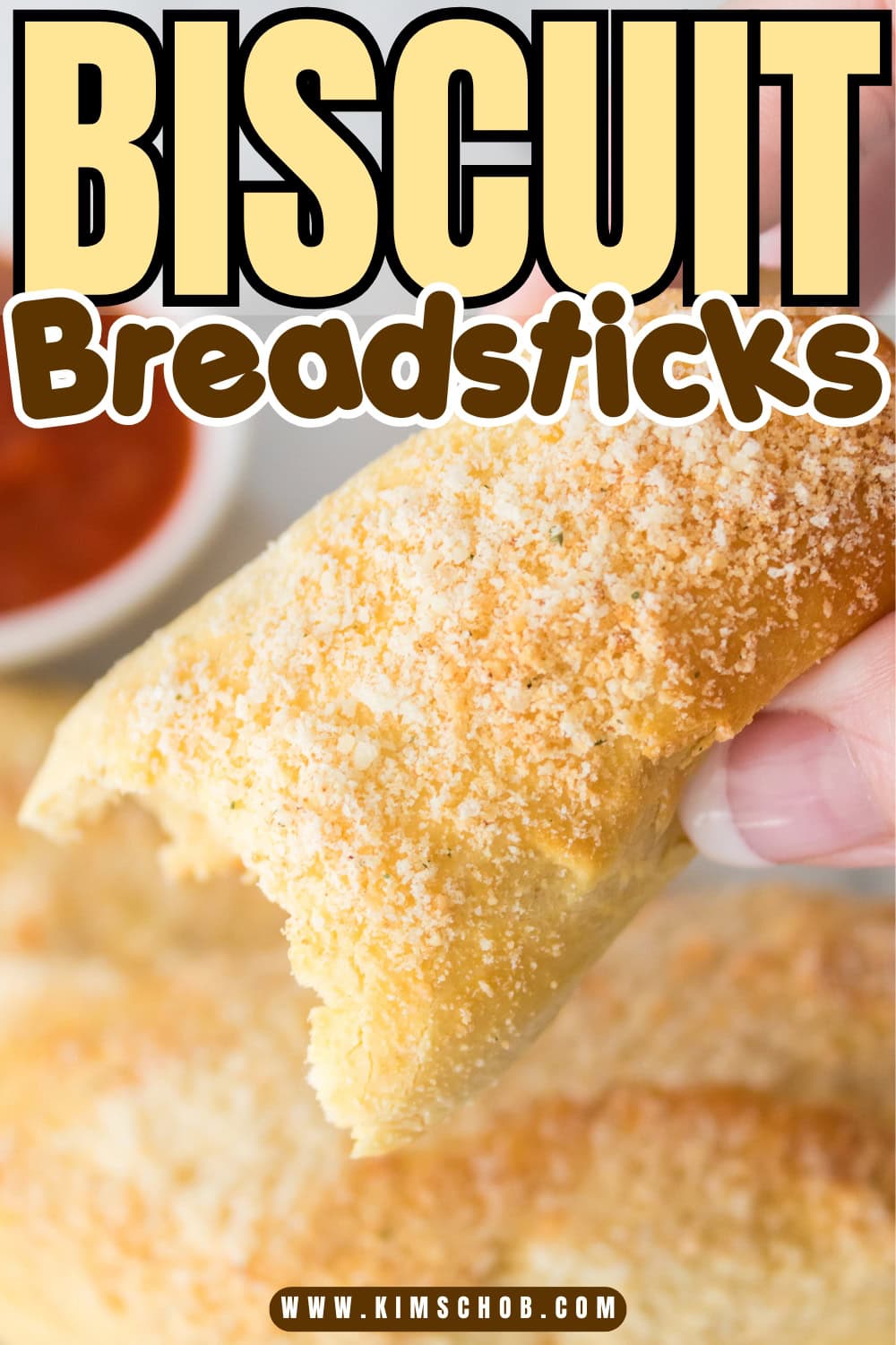 Hand holding a cheesy biscuit breadstick.