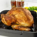 Seasoned roasted whole turkey in a black pan, prepped with Cajun Turkey Brine.