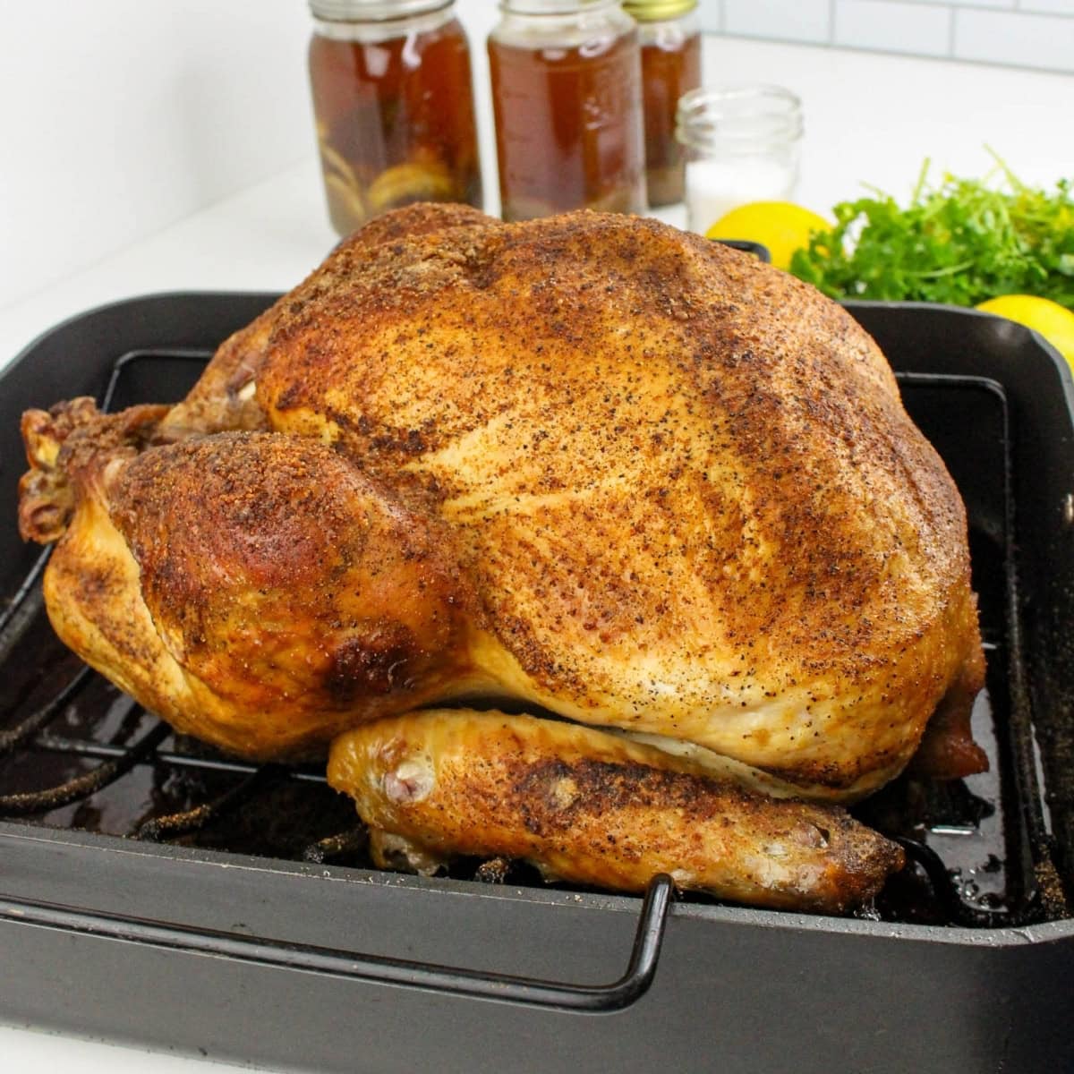 Seasoned roasted whole turkey in a black pan, prepped with Cajun Turkey Brine.
