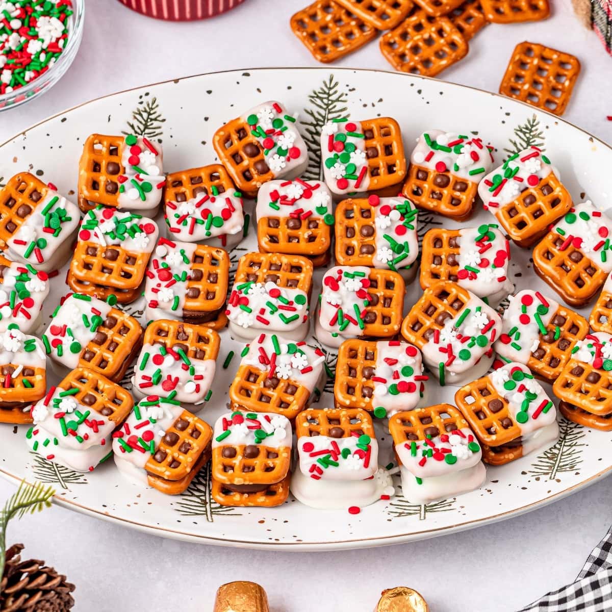 Plate of pretzel bites with white frosting and festive sprinkles.