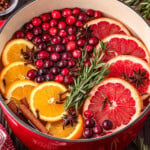 Sliced citrus, cranberries, and spices in a pot for holiday simmering.