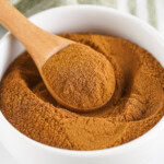 Wooden spoon in a white bowl of spice blend.