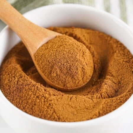 Wooden spoon in a white bowl of spice blend.