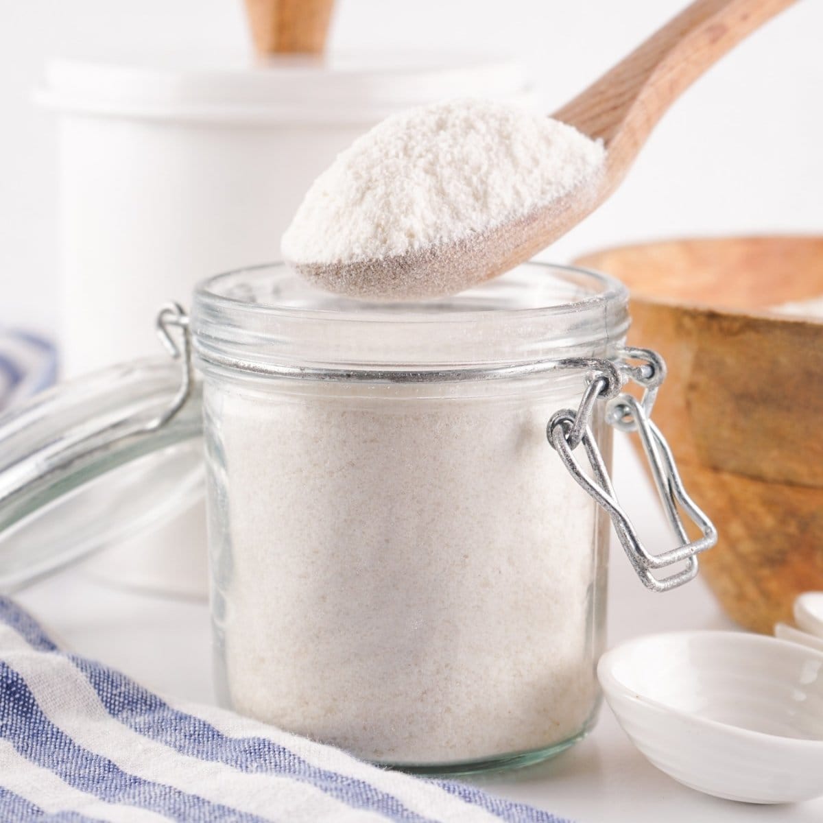 A jar of rice flour alternative with a wooden spoon scooping some out.