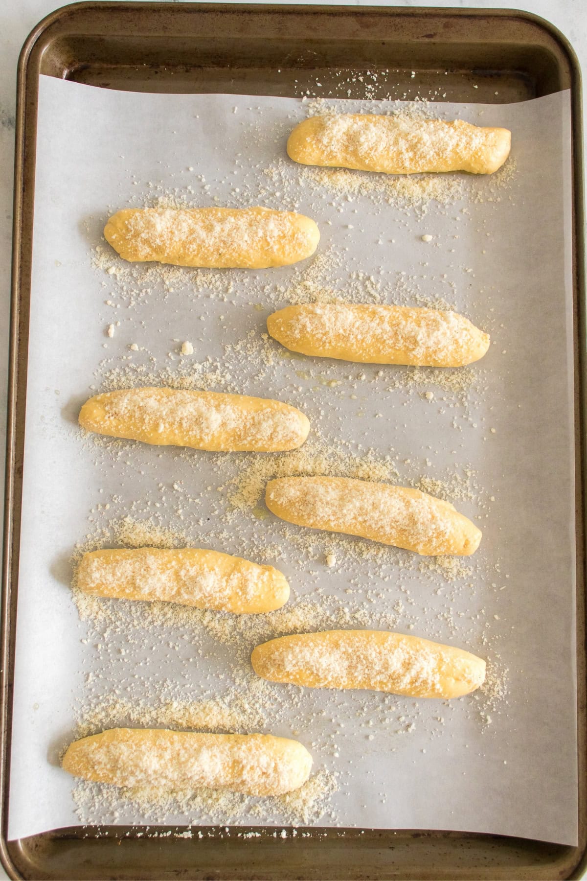 Baking sheet with nine unbaked breadsticks.