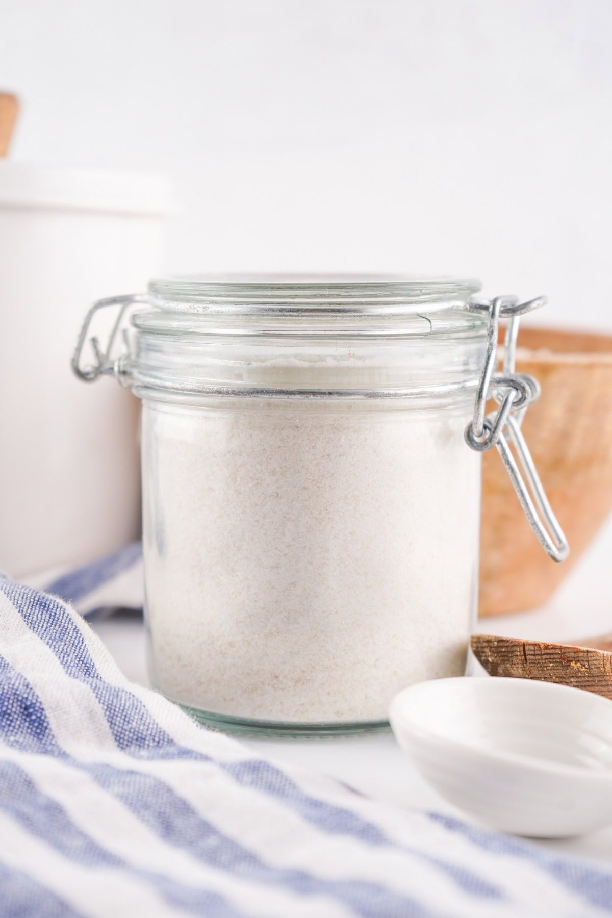 Glass jar of flour on a countertop.