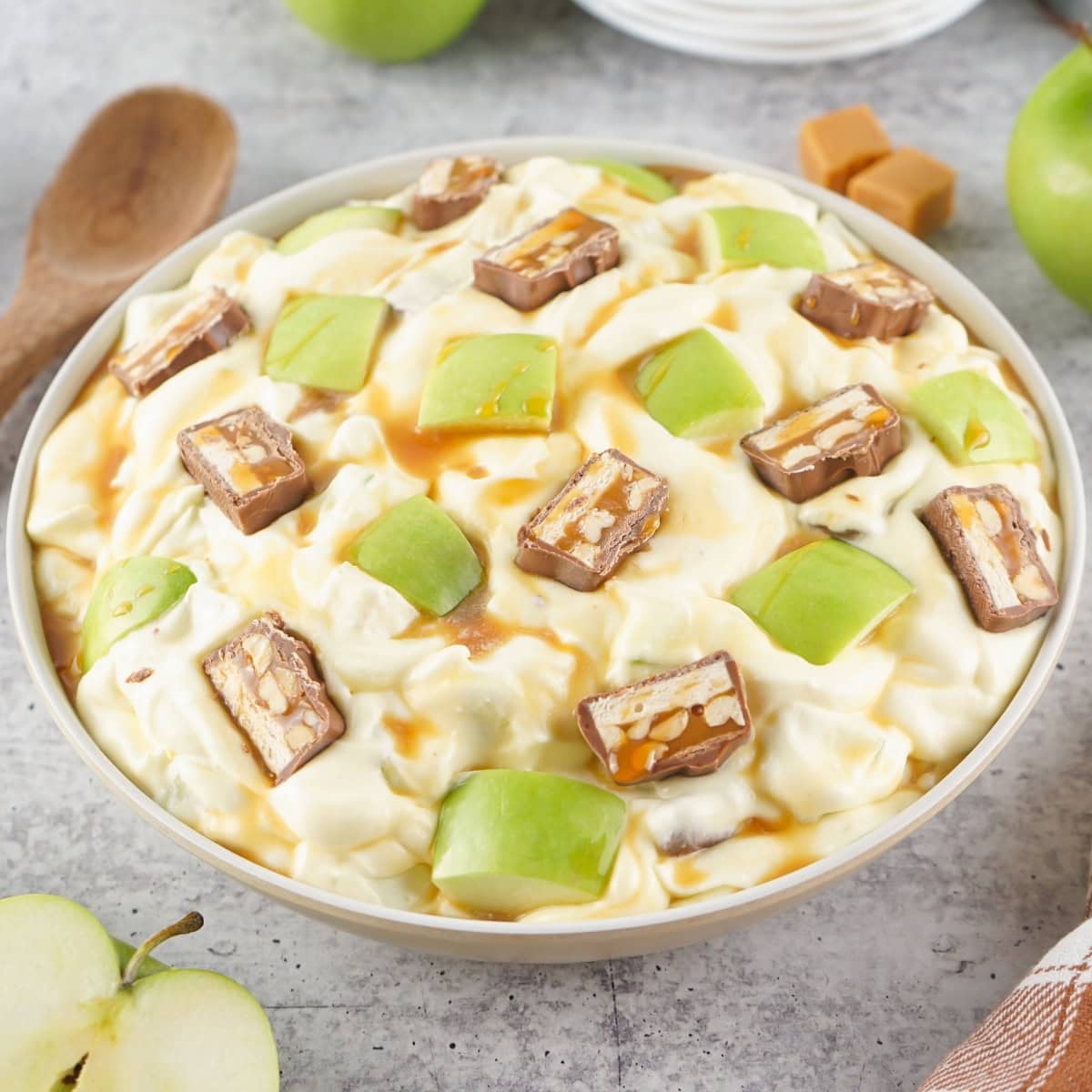 Bowl of vanilla pudding with green apple chunks and candy bar pieces.