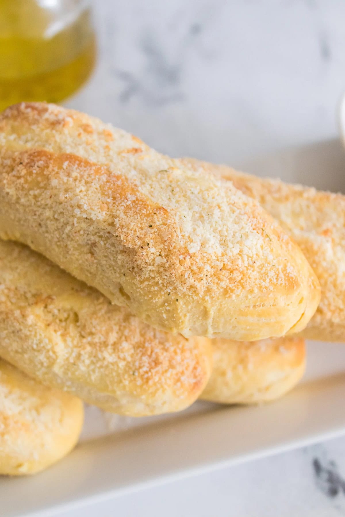 A stack of breadsticks with a sprinkle of grated cheese on top.
