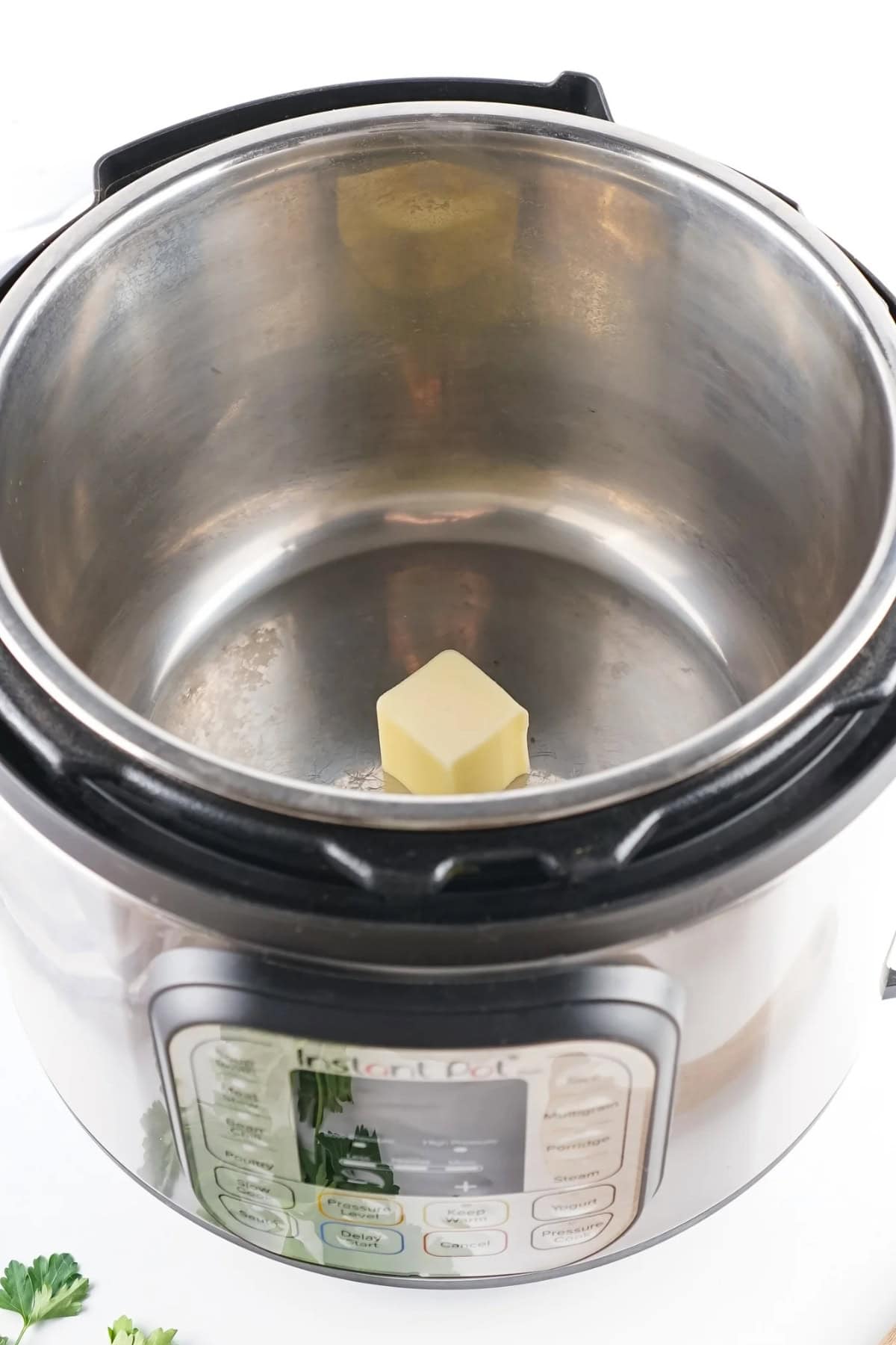 Open Instant Pot with a cube of butter inside.