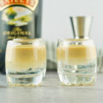 Two layered cocktail shots on a counter.