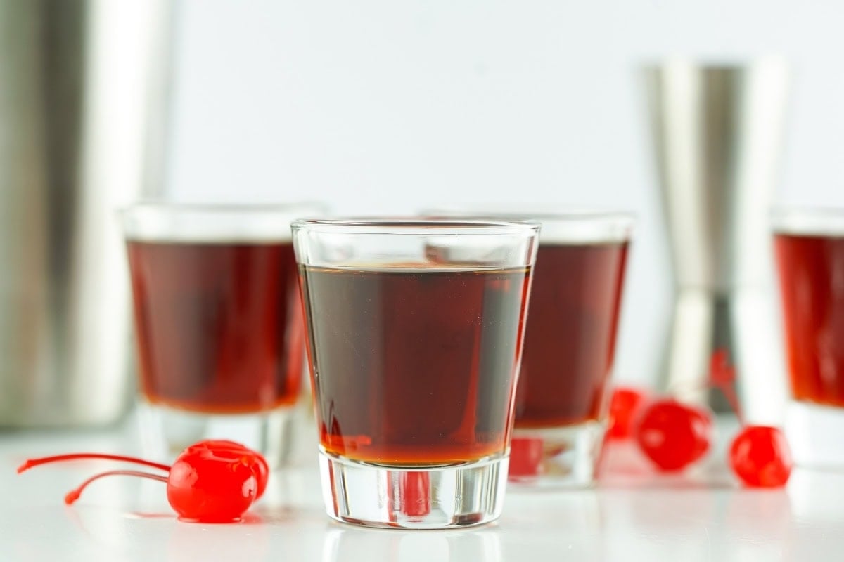 Shot glasses filled with Redheaded slut, surrounded by red cherries.