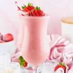 Two strawberry smoothies in tall glasses with striped straws and fresh strawberries.
