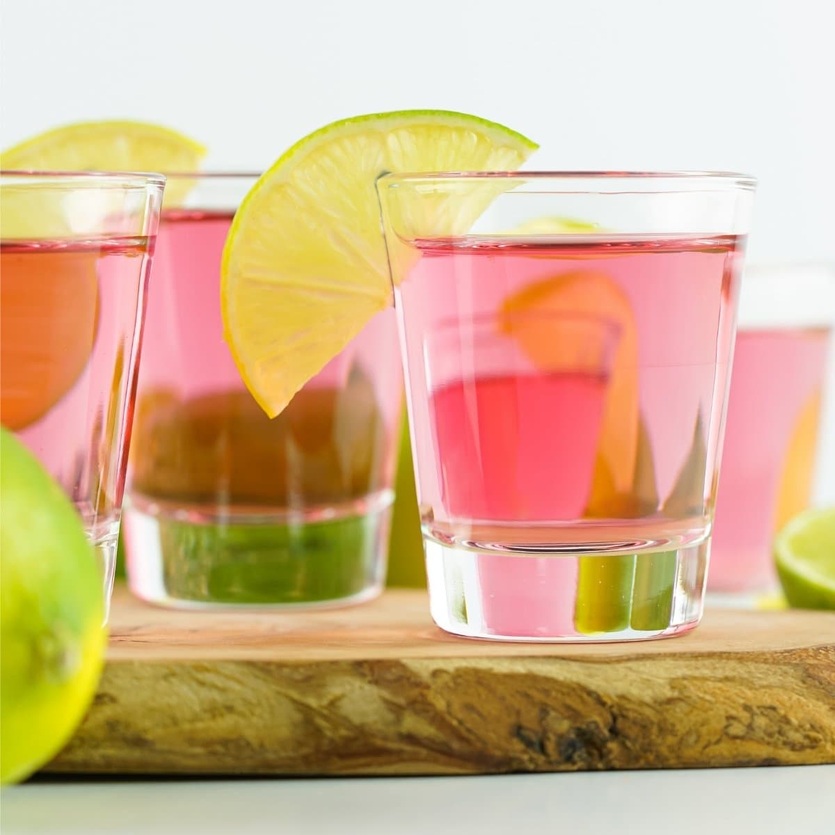 Pink cocktails with lime slices on a wooden board.