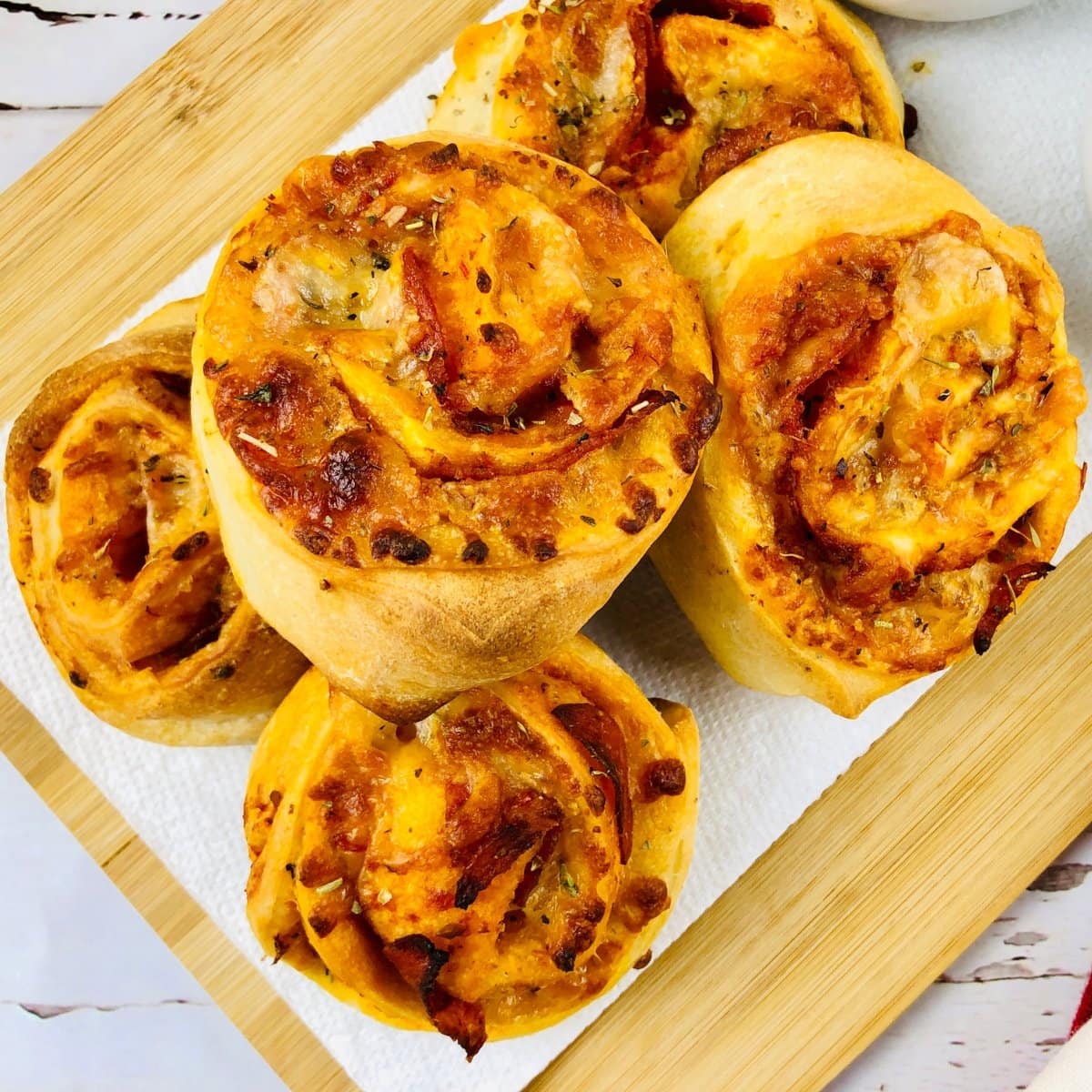 Cheesy pizza rolls with herbs on a wooden board, ready to serve.