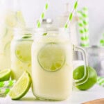 Jar of creamy lime drink with lime slices and green striped straws.