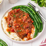 Plate with swiss steak, mashed potatoes, and green beans.