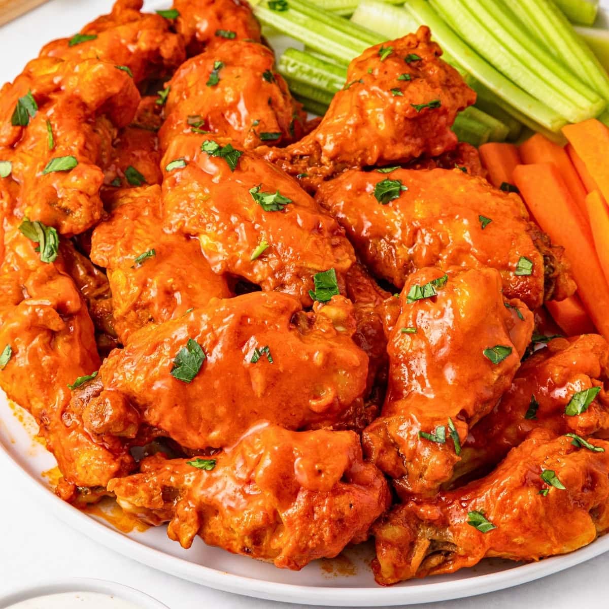 Plate of buffalo chicken wings with celery and carrot sticks.