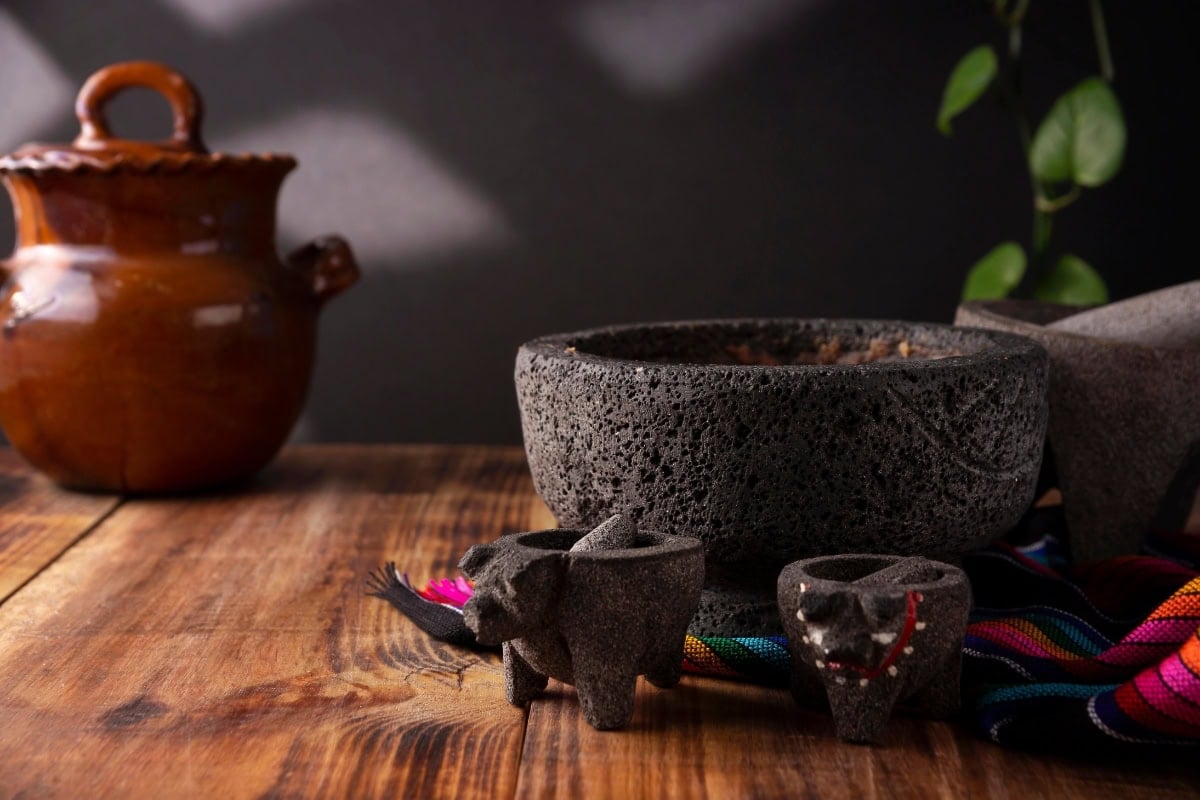 Stone mortar and pestle with decorative figures on a wooden table.