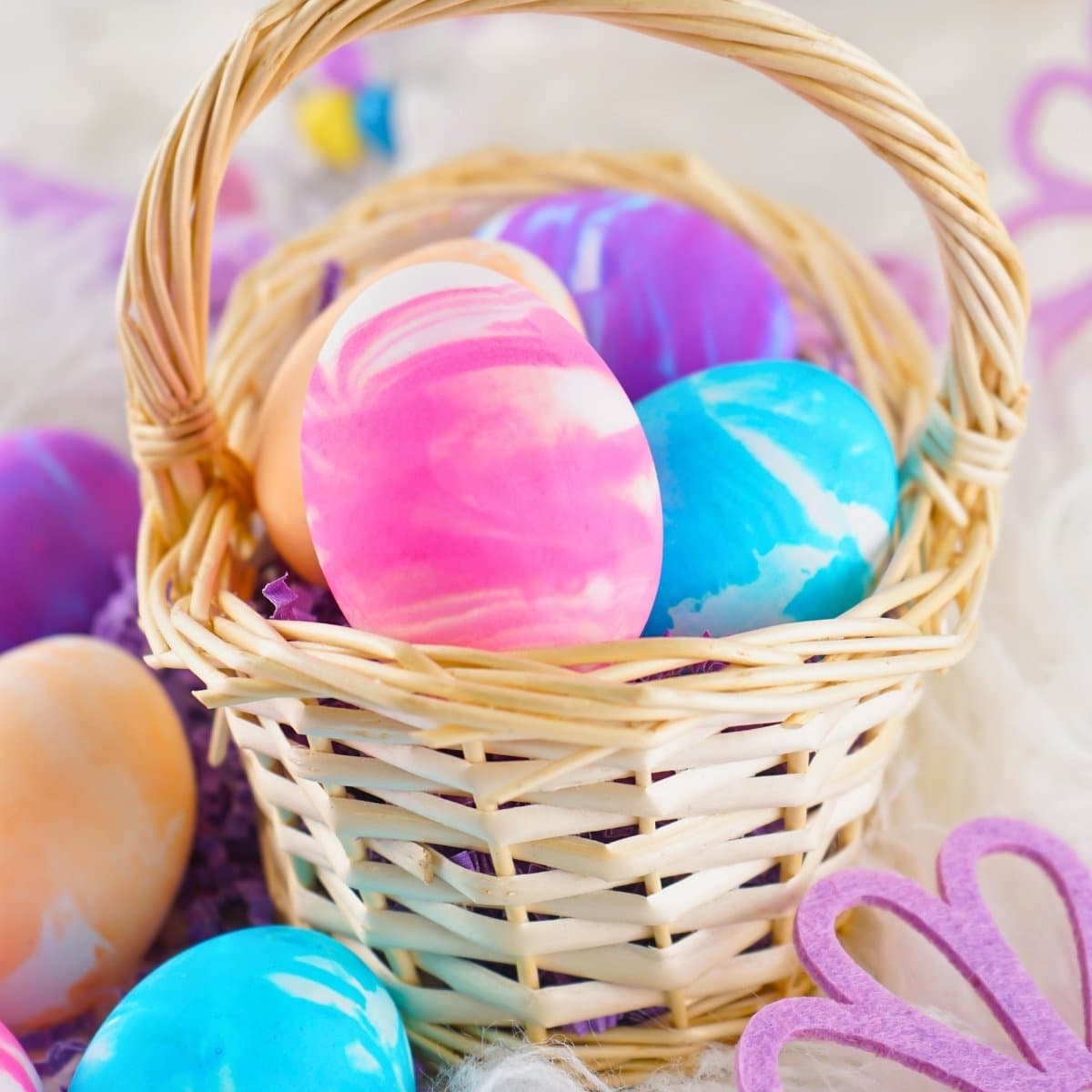 Basket with colorful marbled Easter eggs on soft, fuzzy fabric.