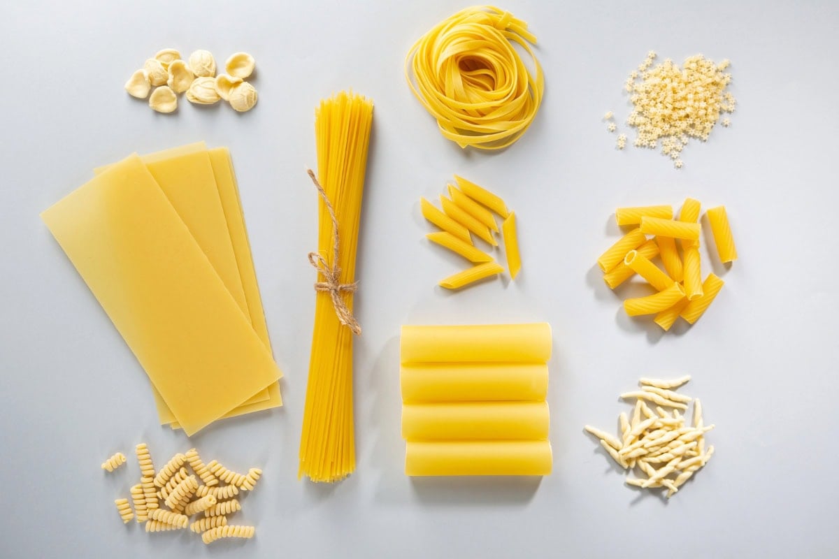 Various uncooked pasta shapes arranged neatly on a light surface.