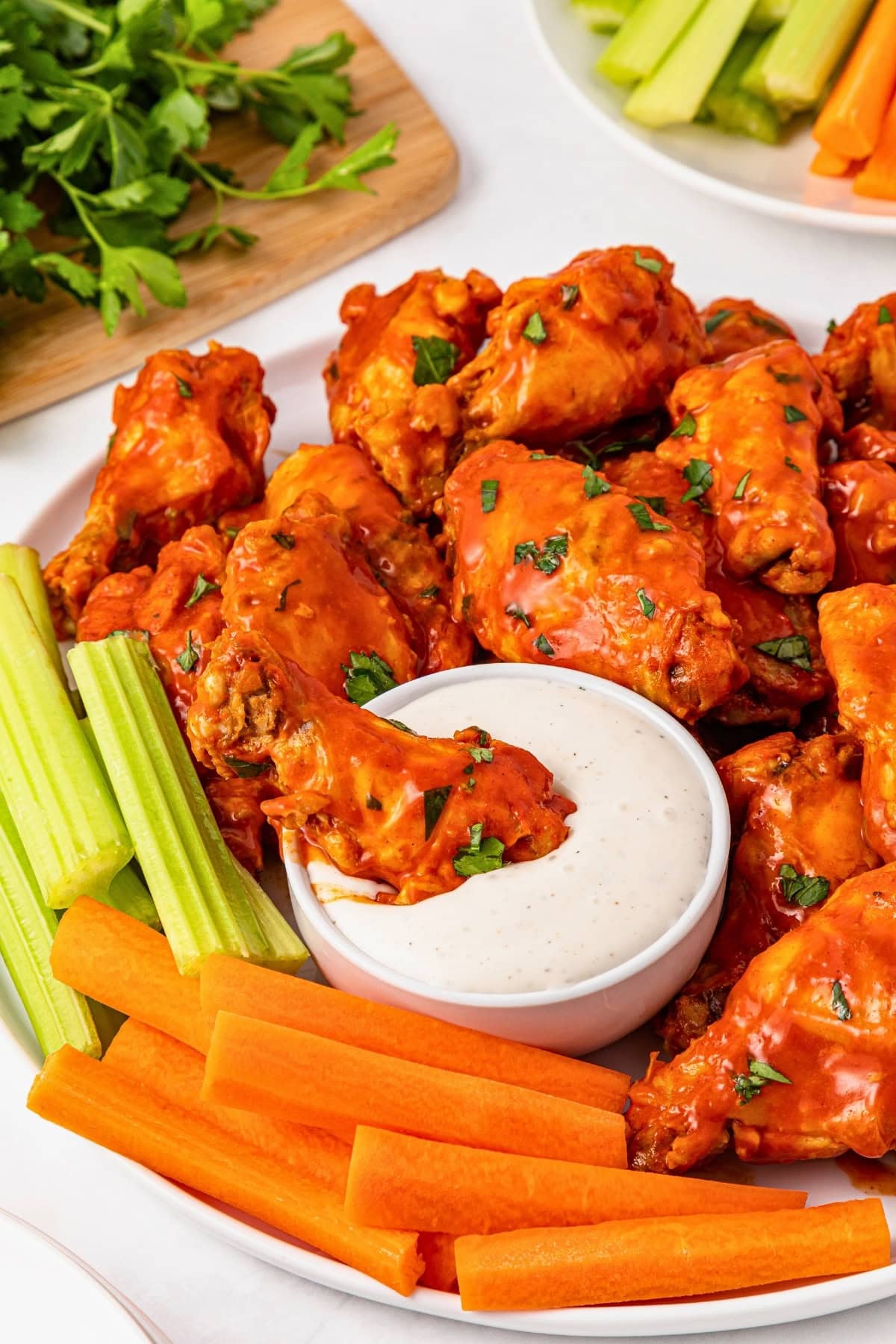 Buffalo chicken wings with ranch dip, celery, and carrot sticks on a platter.