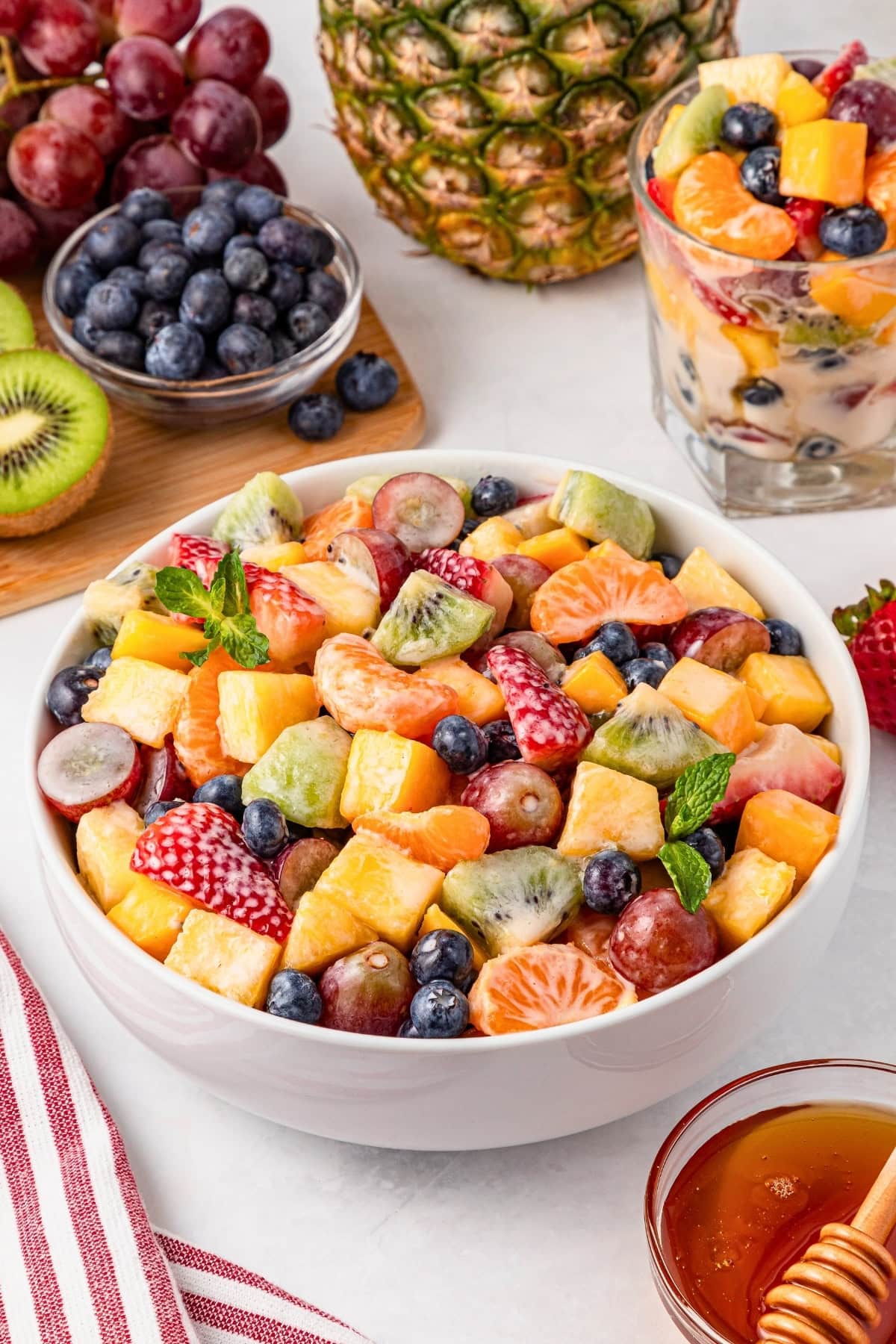 A bowl of mixed fresh fruit salad with grapes, kiwi, oranges, and berries.