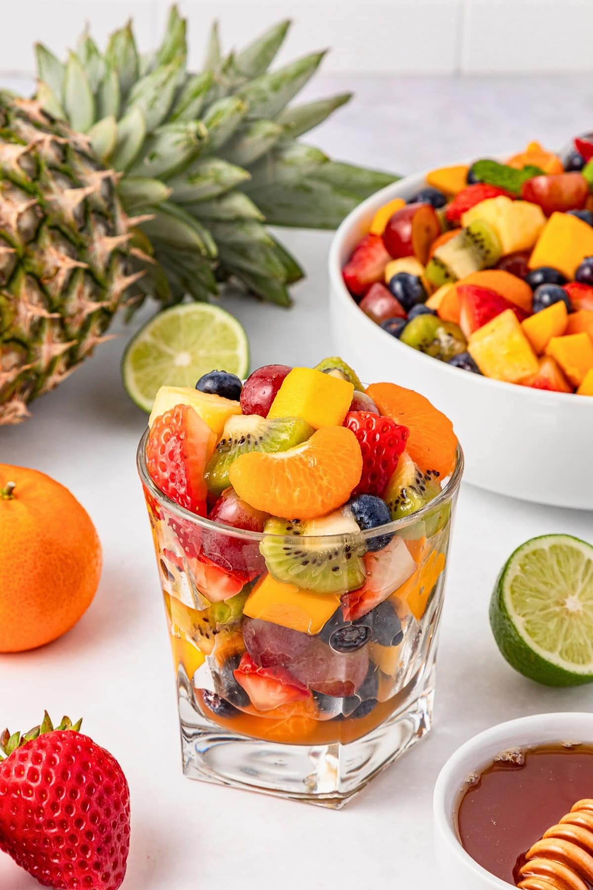 Glass of mixed fruit salad with grapes, kiwi, strawberries, and citrus slices.