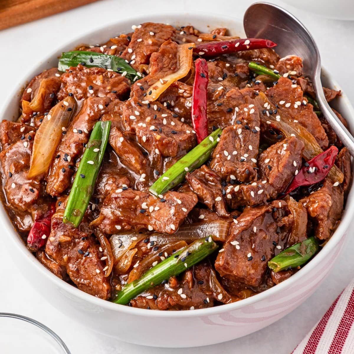 Slow Cooker Mongolian Beef stir-fry with green onions, chilies, and sesame seeds.