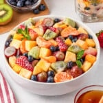 A bowl of colorful mixed fruit salad with strawberries, grapes, kiwi, and oranges.