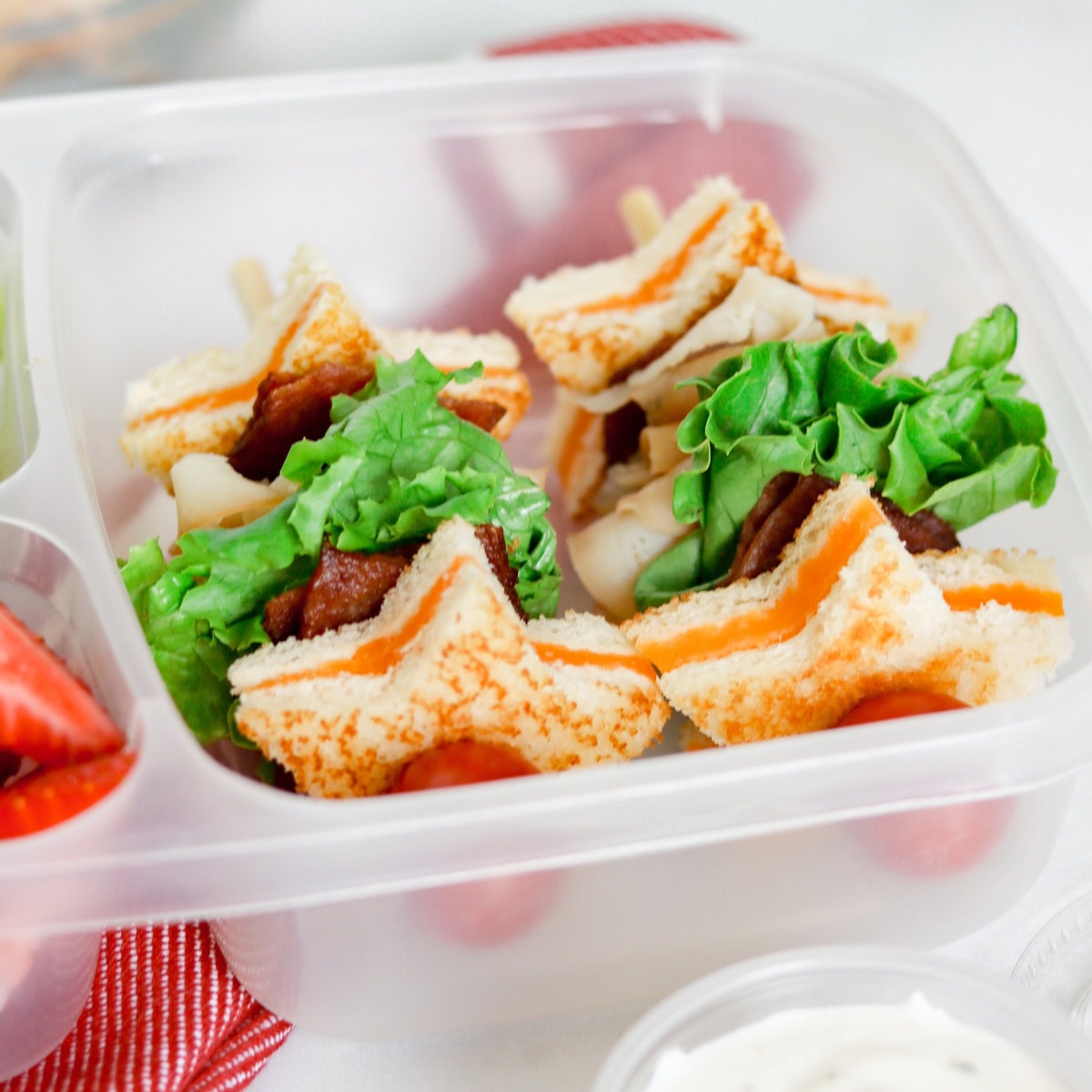 Star-shaped sandwich skewers with lettuce in a lunchbox compartment.