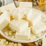 A plate of white chocolate coconut fudge squares topped with shredded coconut.