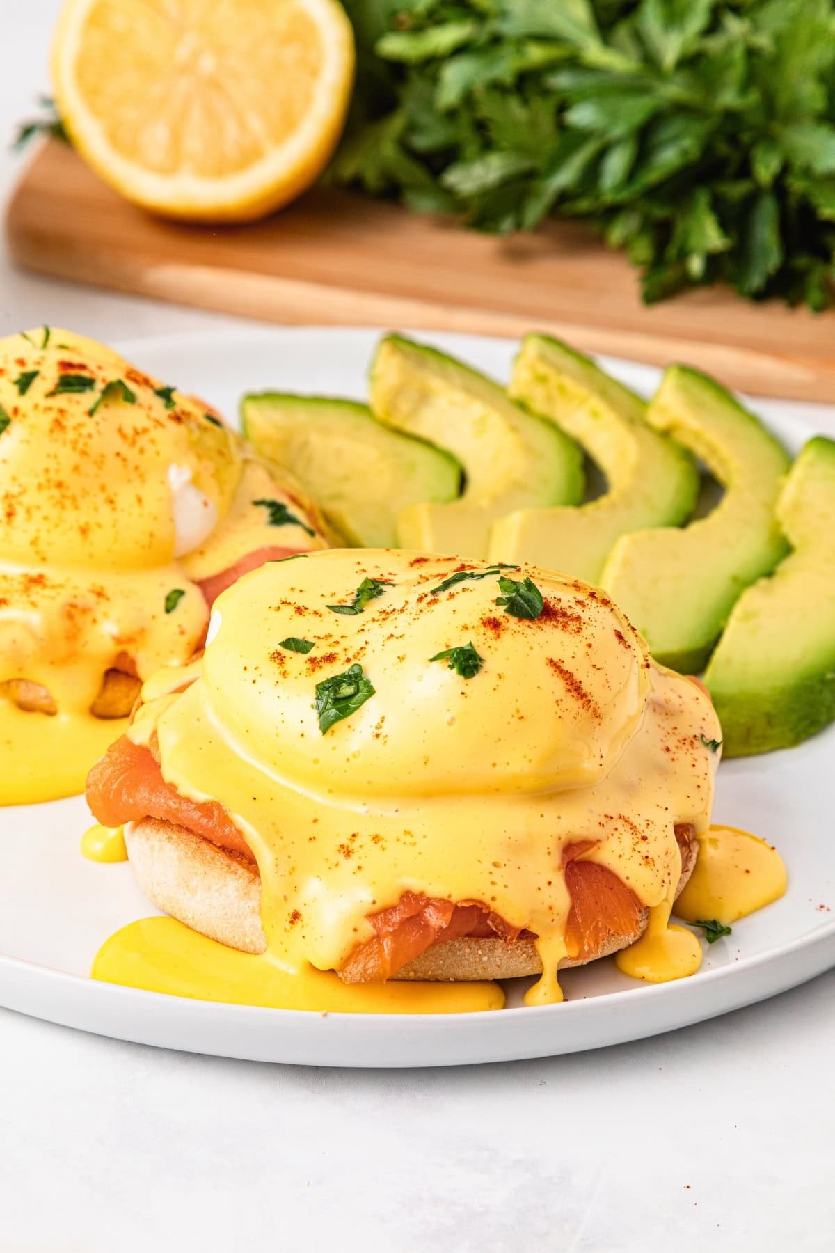 Eggs Benedict with smoked salmon and hollandaise sauce, served with sliced avocado.