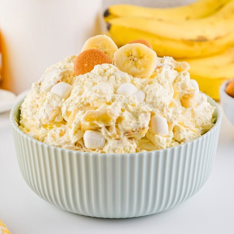 Banana fluff pudding with marshmallows and wafers in a light blue bowl.