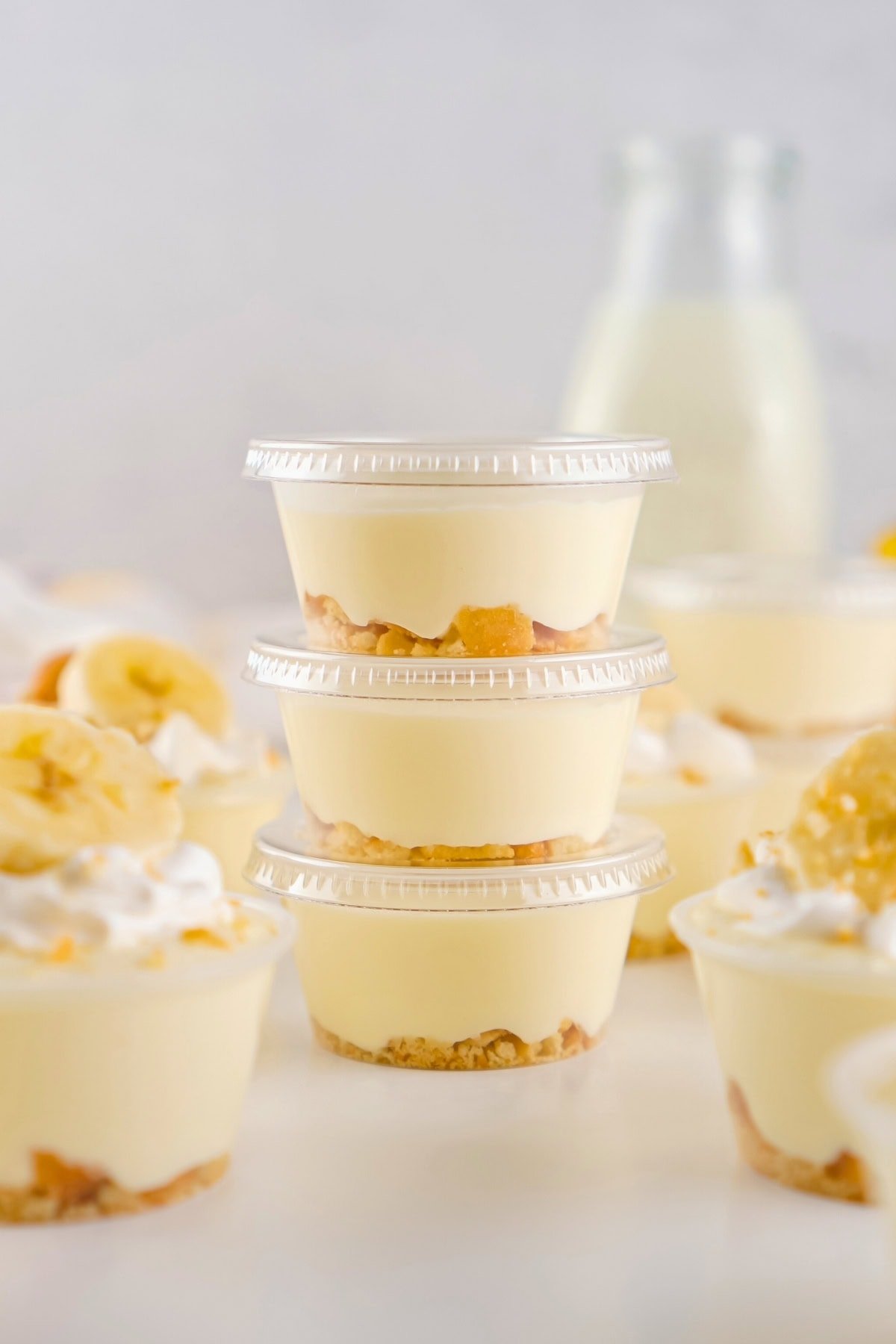 Four stacked banana pudding cups with a milk bottle in the background.
