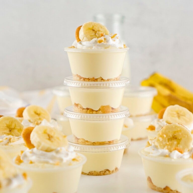 Stacked Banana Pudding Shots topped with whipped cream and banana slices.