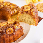 A slice of banana upside-down cake being lifted from the whole cake.