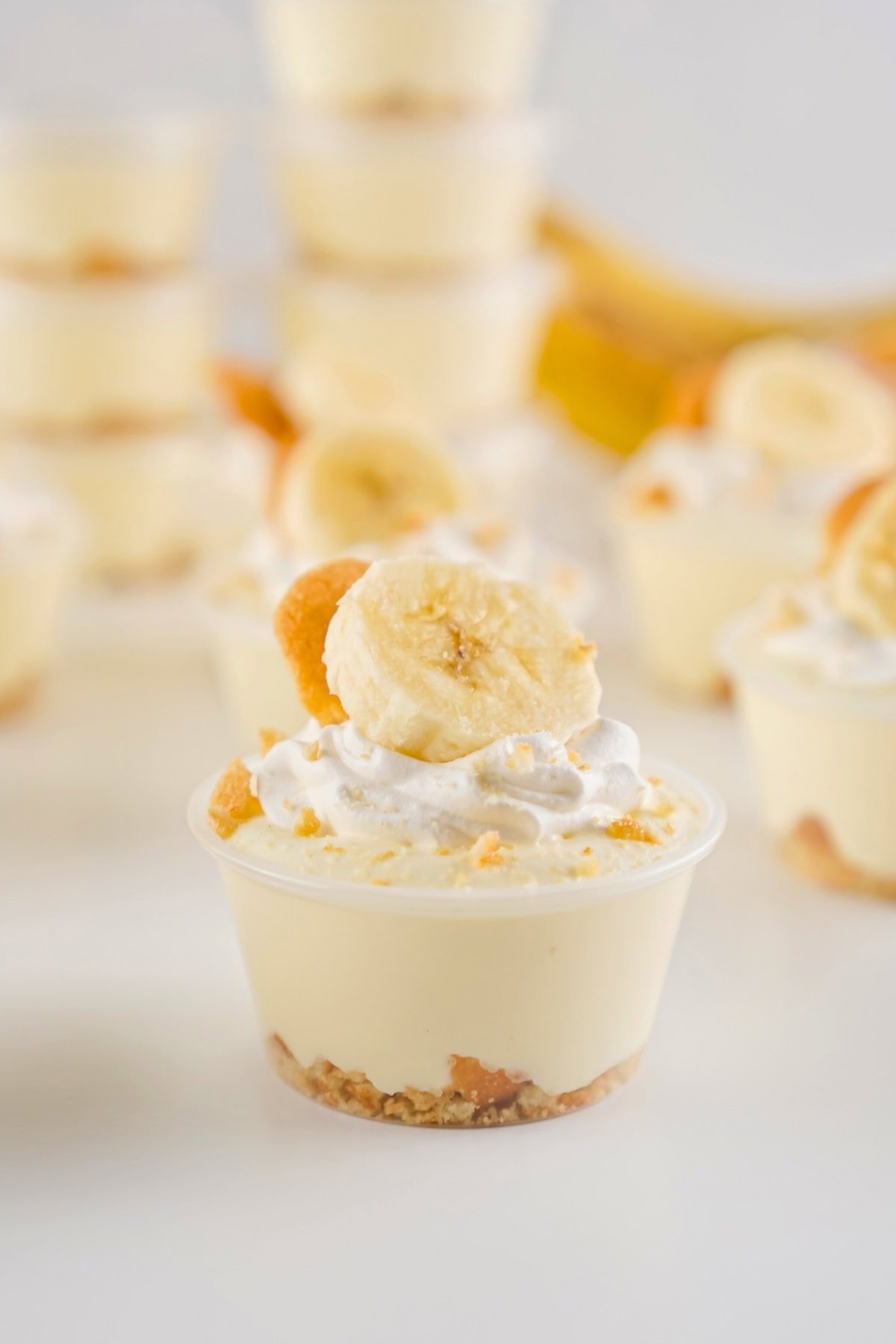 Mini banana pudding cup topped with whipped cream and a banana slice.
