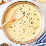 Creamy Alfredo sauce in a pan, topped with chopped parsley and black pepper.