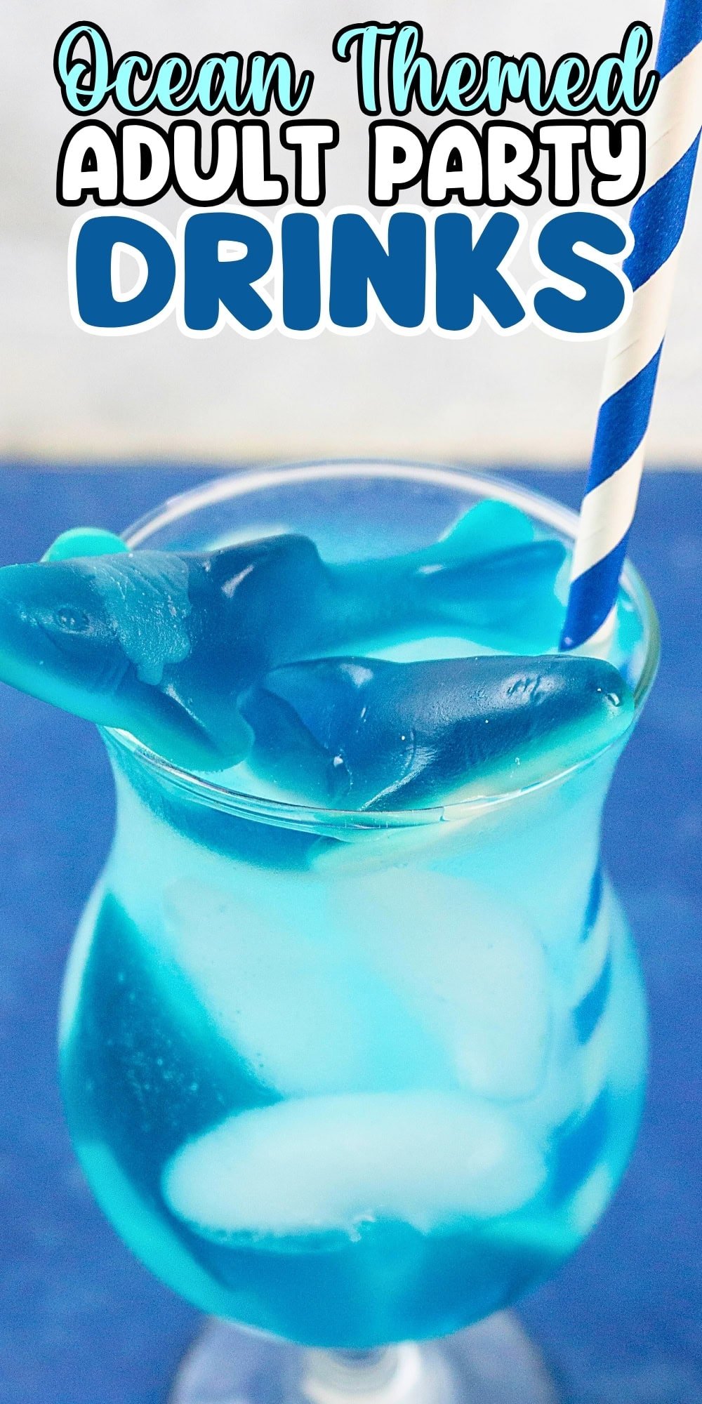 Blue cocktail with ice, gummy sharks, and a striped straw; ocean party theme.