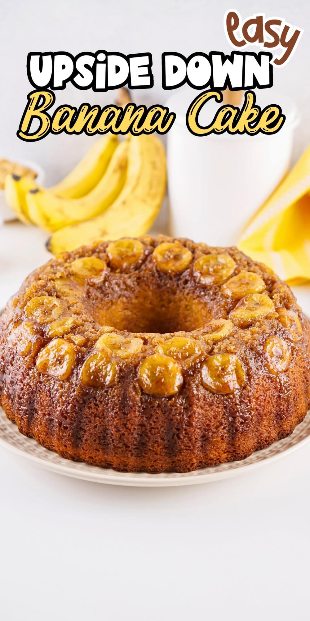 Round upside-down banana cake on a plate with bananas in the background.