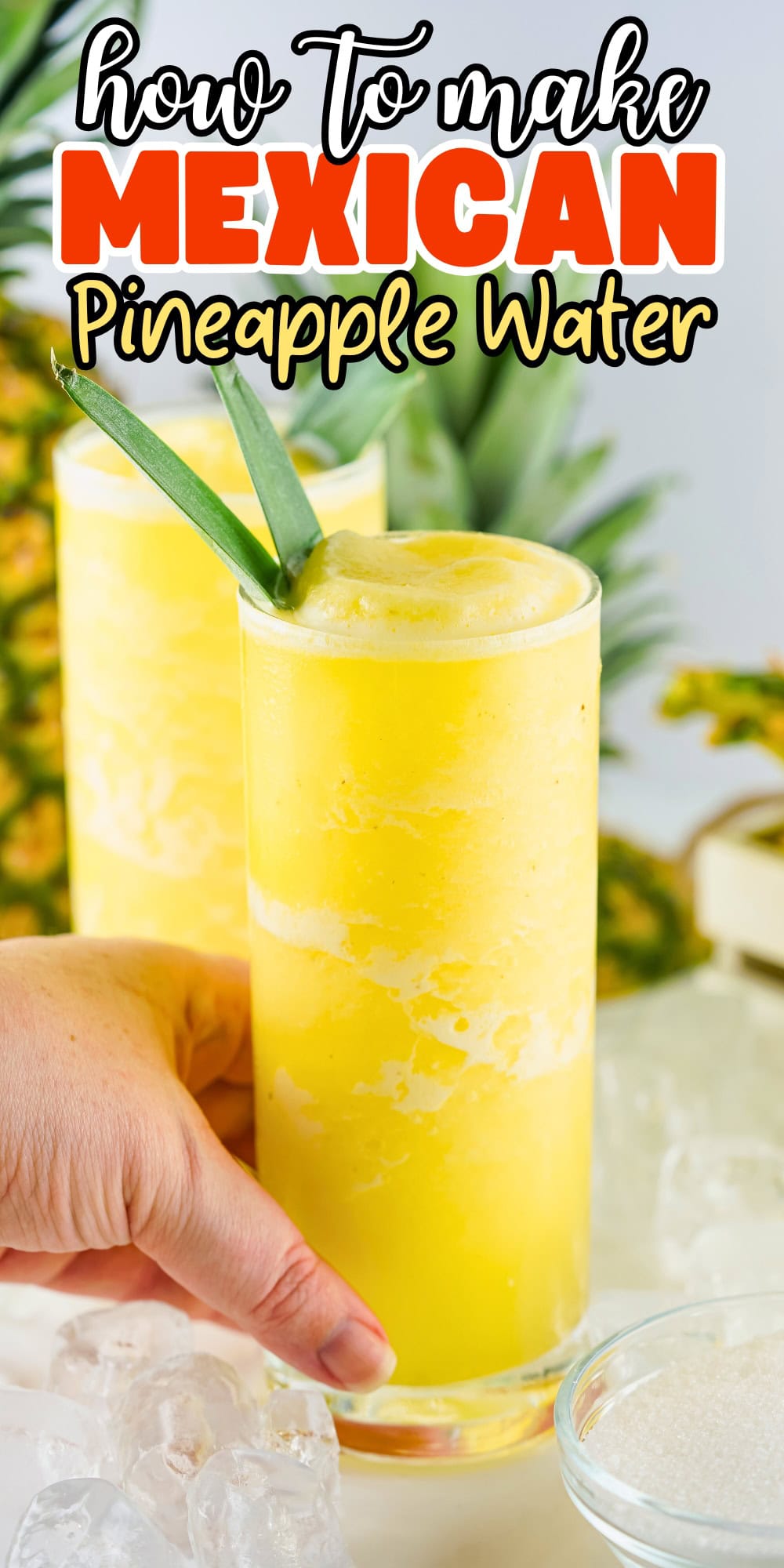 Two tall glasses of bright yellow pineapple water, garnished with pineapple leaves.