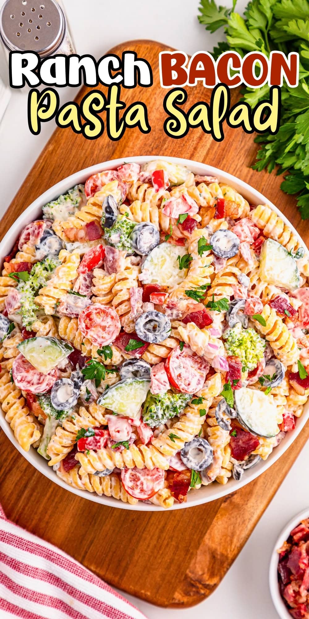 A bowl of ranch bacon pasta salad with veggies on a wooden board.