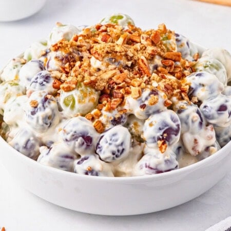 A bowl of creamy grape salad topped with chopped pecans.