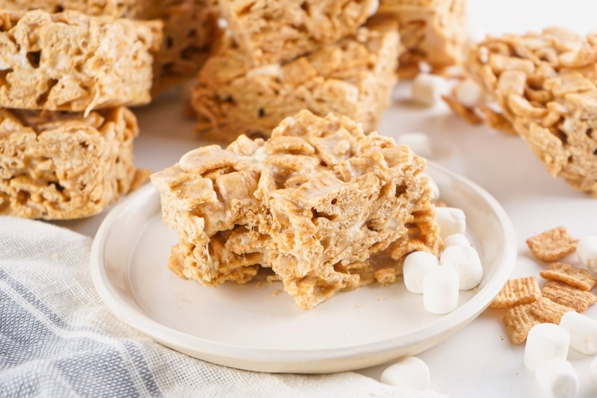 A plate with cereal marshmallow bars and mini marshmallows on the side.